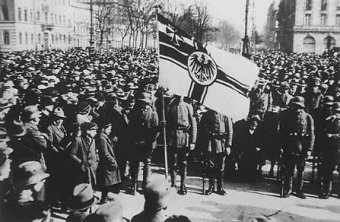 A crowd of people on the street with a flag