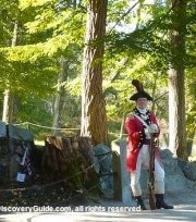 Redcoat reenactor standing next to British casualty memorial at Old North Bridge in Concord, MA